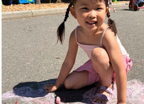 A Preschool student in the recess area smiling at us